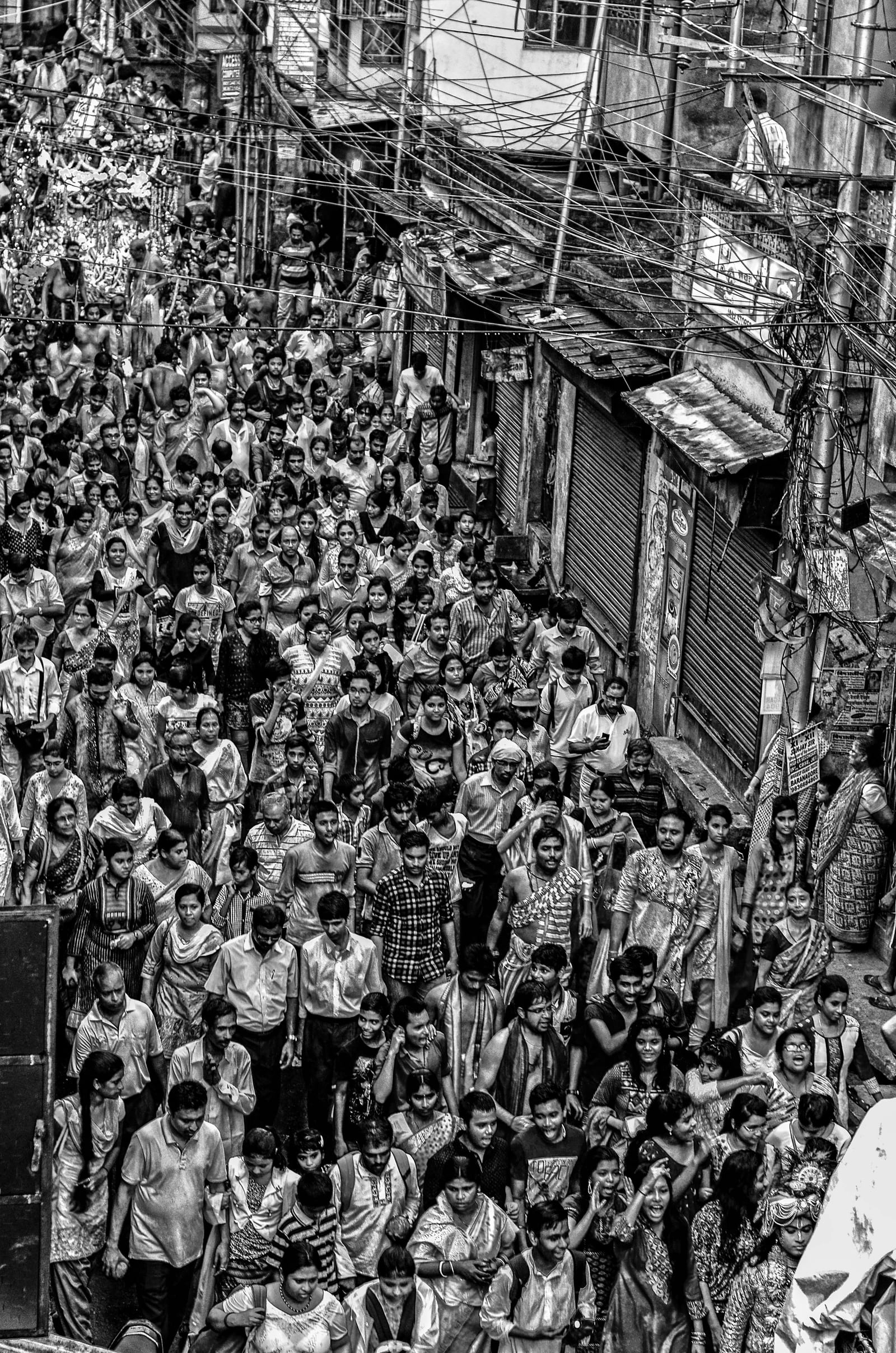 Dense crowd filling a narrow Indian street, photographed from above in black and white